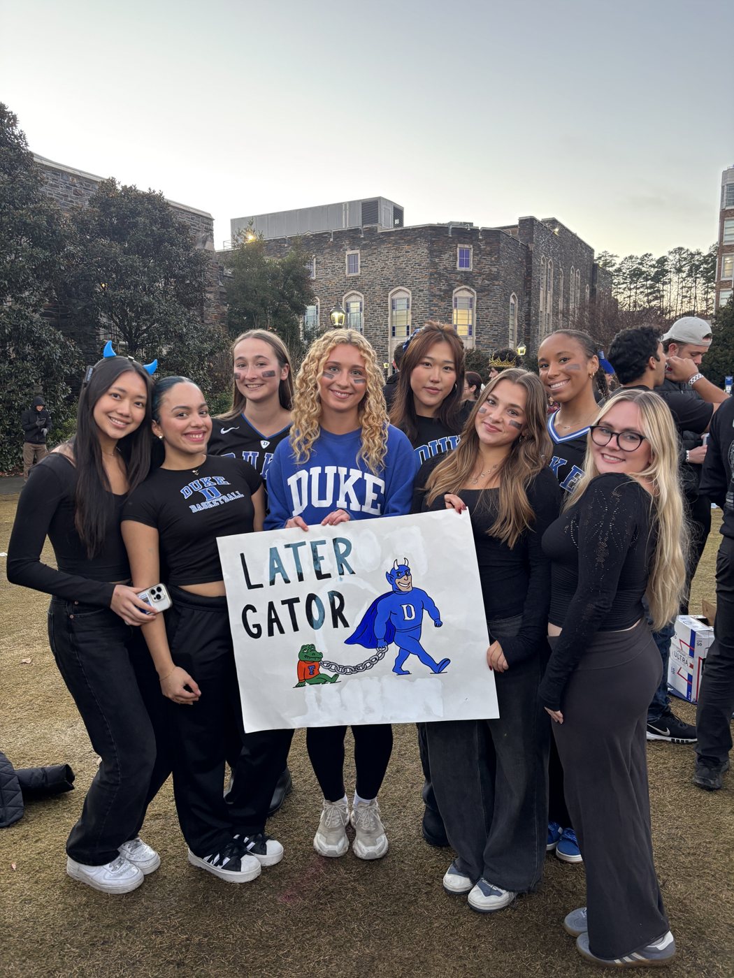 Friends holding a hand-painted Later Gator sign before the game