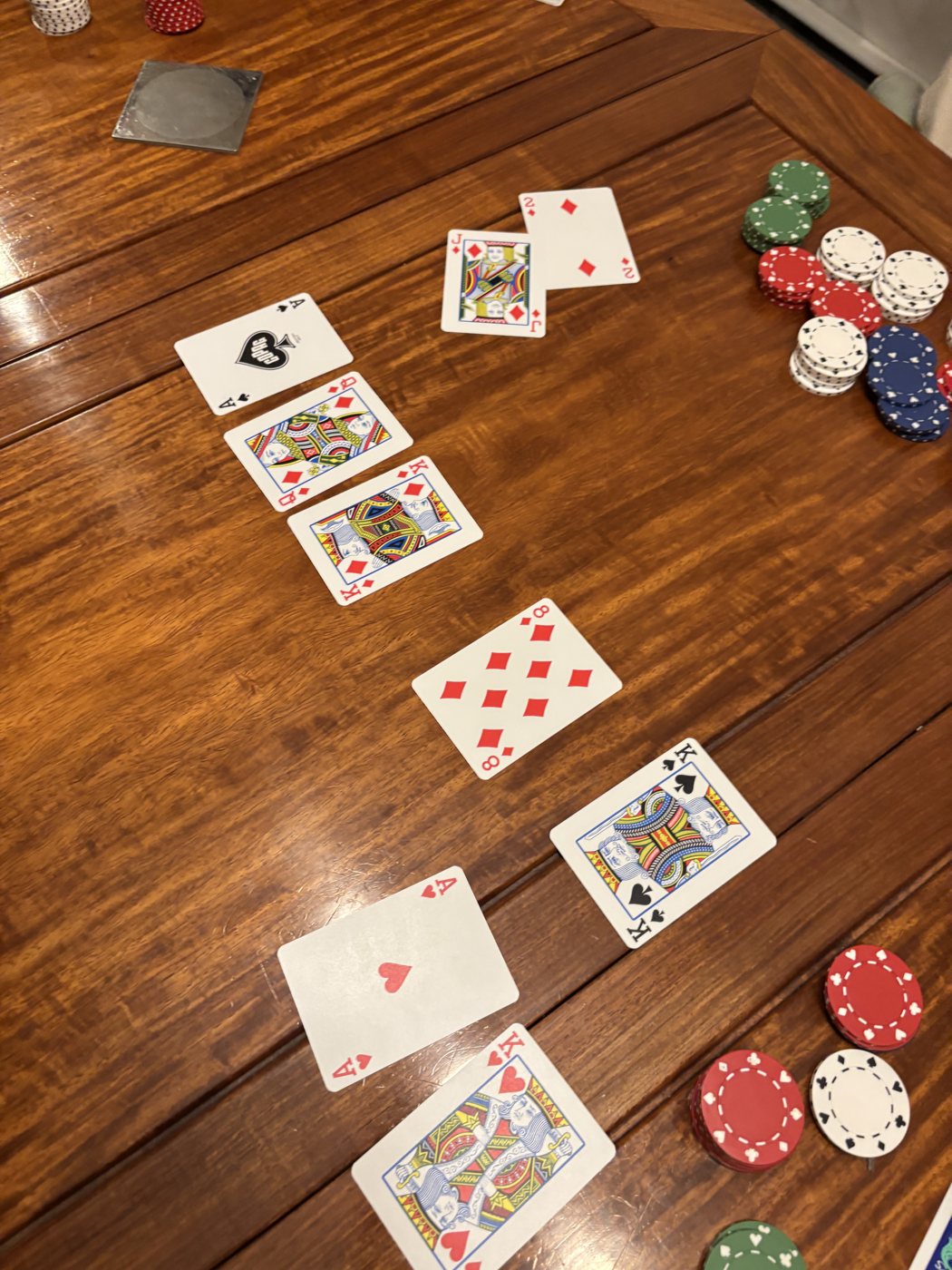 Cards and poker chips spread across a wooden table mid-game
