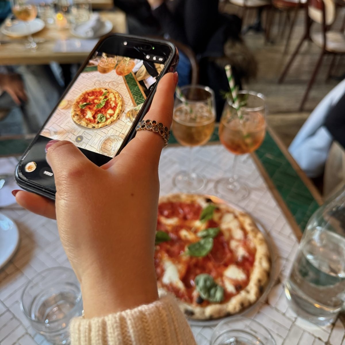 Photographing a fresh pizza at a restaurant table