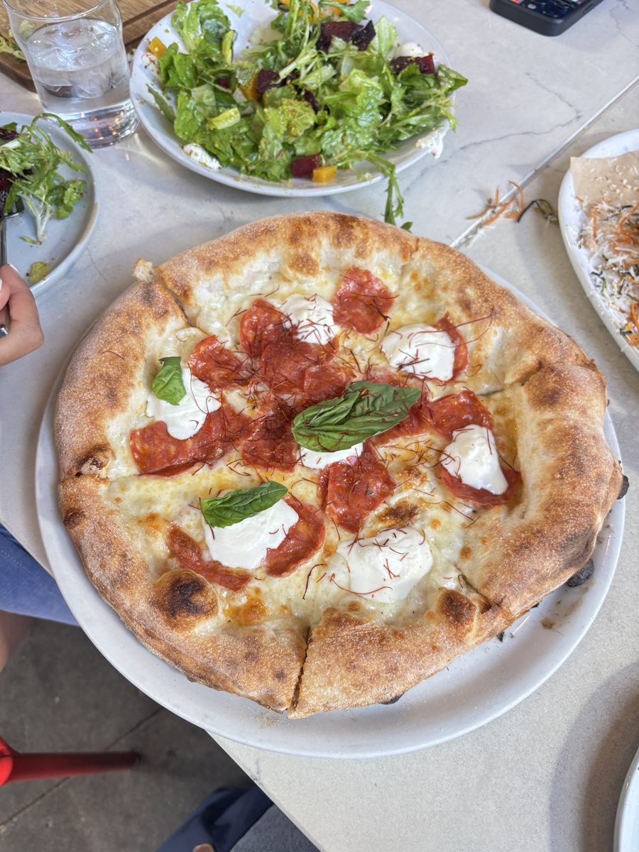 A margherita pizza with basil next to a green salad
