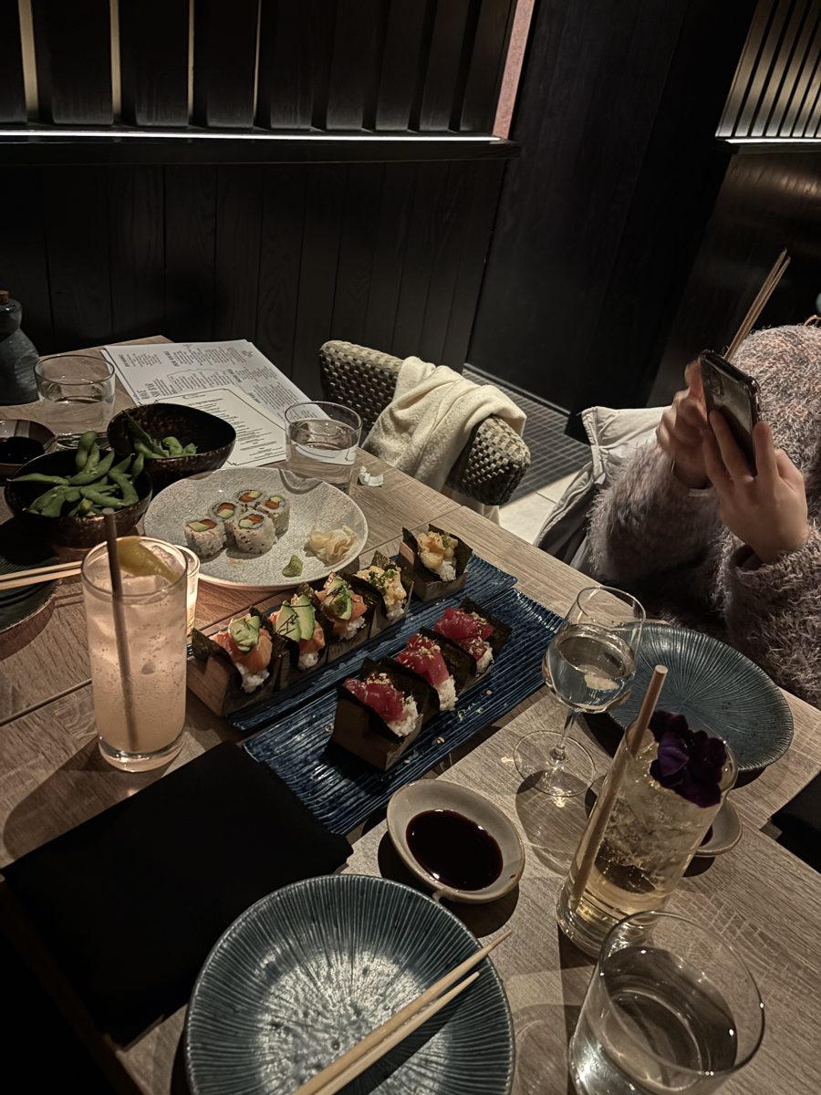 A dark sushi bar counter with handrolls and small plates