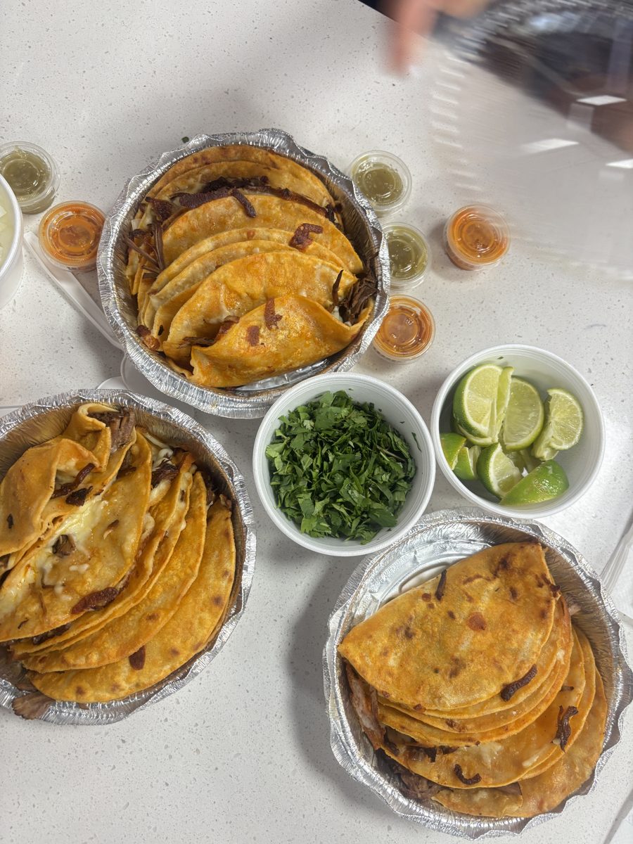 Birria tacos with limes, cilantro, and consommé seen from above